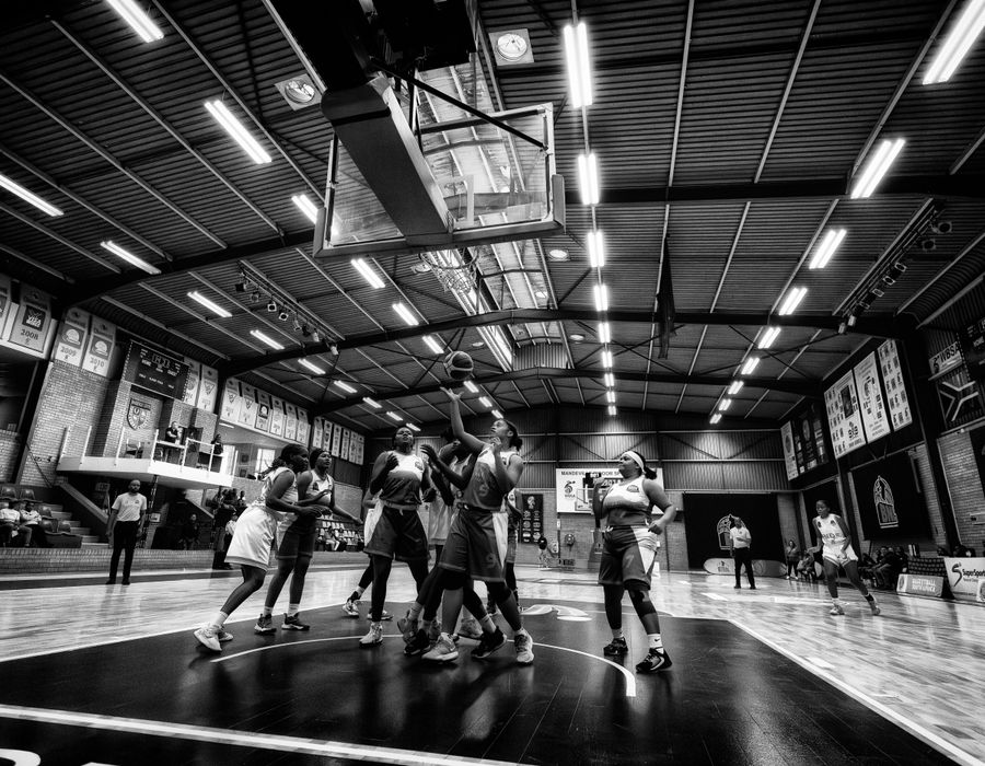 Jogador de basquete enterrando a bola em ginásio
